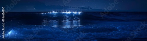 Bioluminescent waves breaking at night on a beach shoreline under a starry sky, showing natural light phenomenon.