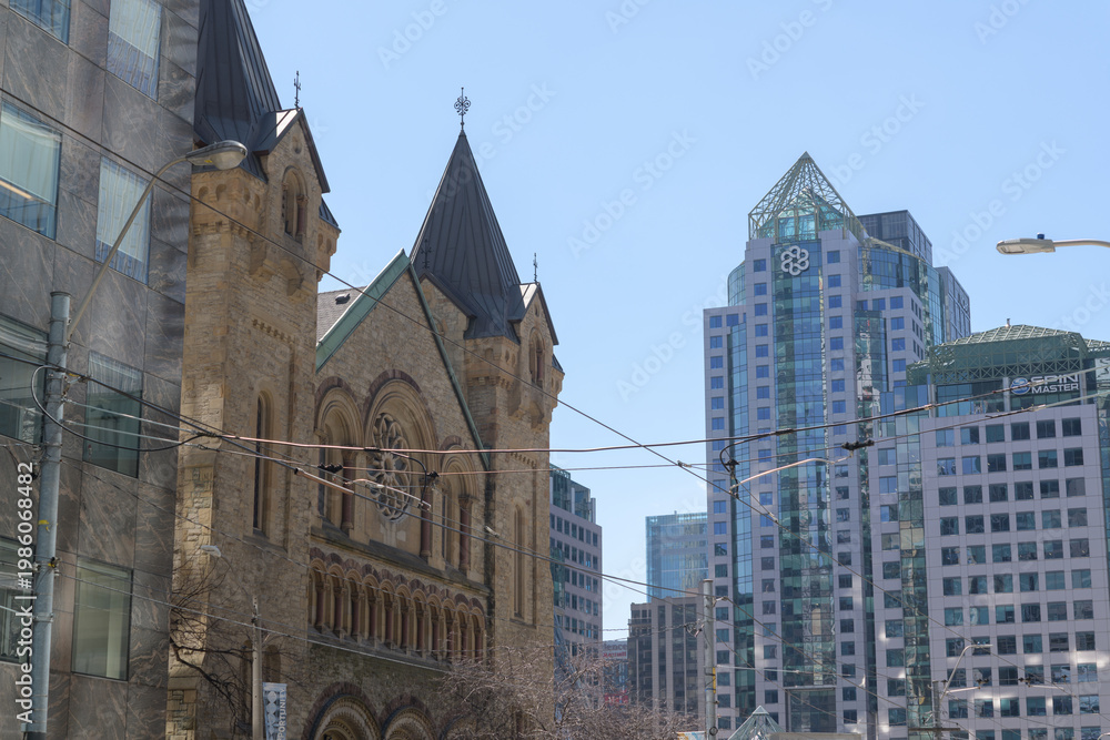 Obraz premium a view of Metro Hall (55 John St), a municipal office complex and facade of St. Andrew's Presbyterian Church (73 Simcoe St), looking west on King St W, Toronto