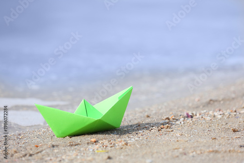 Green paper boat on sand ne...