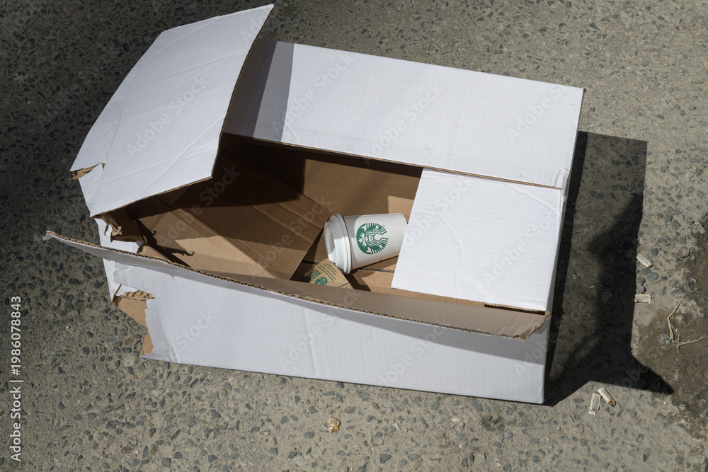 Fototapeta premium discarded Starbucks coffee cup in an old white cardboard box on the street, Toronto