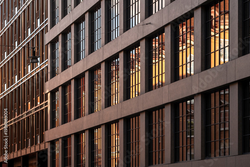 Urban warm atmosphere around modern office windows as symmetry pattern repeats across architecture building facade suggesting late work and city life