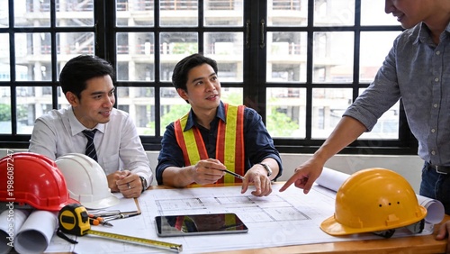 Construction Engineers and Architects Discussing Building Blueprint at Office Table