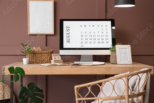 Modern PC monitor with calendar, mobile phone and books on wooden table near ...