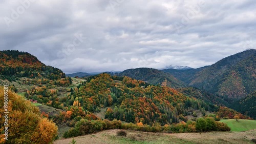 Autumn mountain landscape with colorful forest under cloudy sky timelapse