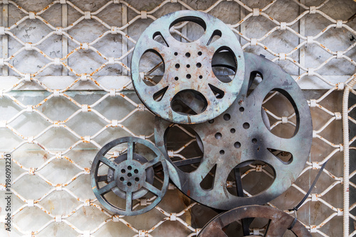 Decorative arrangement of rusty cinema film reels on a white metal grid background.