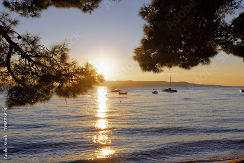 Sea with ships and beach of Makarska on the Riviera at sunset, in Dalmatia in late summer