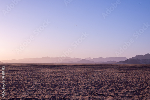 Golden dunes rise like waves frozen in time, stretching endlessly under a sky painted with soft pastels, where solitude and silence reveal the raw soul of Namibia’s desert.	
