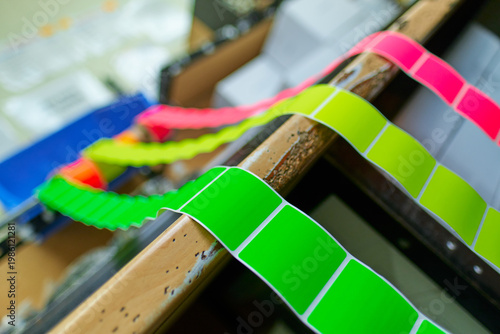 Bright coloured Illuminous adhesive label rolls on an industrial production line in packaging and manufacturing environment. Food labels for health safety and hygiene purposes.