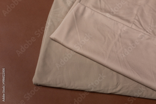 two beige knitted fabrics on a brown background