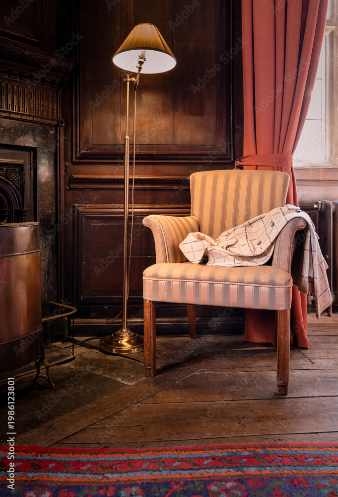 Fototapeta premium Elegant Ladies Coat Draped Ove The Arm Of A Chair In A Period Wooden Panelled Drawing Room