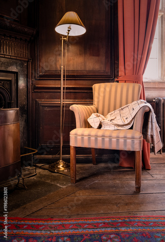 Elegant Ladies Coat Draped Ove The Arm Of A Chair In A Period Wooden Panelled Drawing Room