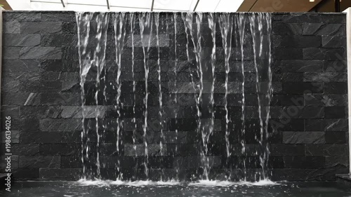 Modern indoor fountain with flowing water against a dark stone wall design