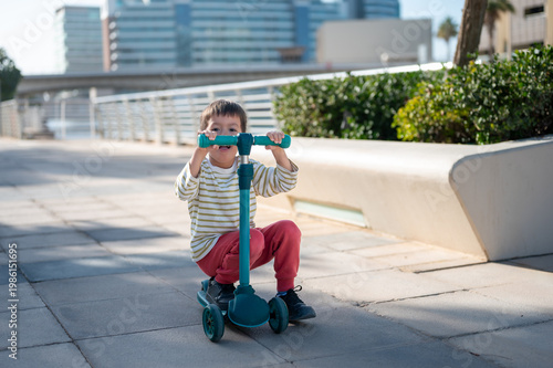 Young Boy Riding a Scooter on a Sunny Day in an Urban Setting