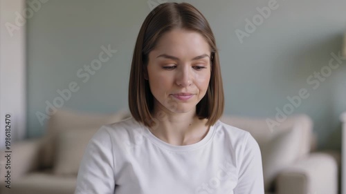 Woman in white shirt looking down at something in her hand indoors