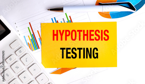Hypothesis testing text on yellow paper with calculator pen and financial charts on desk data analysis concept