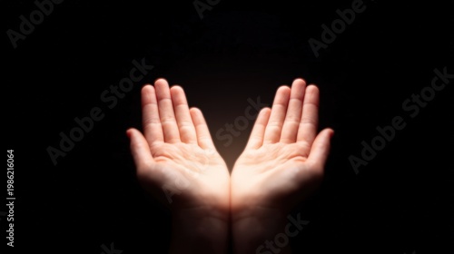 Social justice visual concept, Two open hands illuminated against a dark background, palms facing upward in a gesture of offering or receiving.