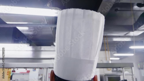 Slow Push-In Behind Unrecognizable Chef Putting On Tall White Hat in Commercial Kitchen - 60fps
