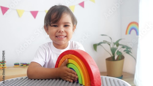 Hispanic little girl playing with development rainbow toy at pre school classroom