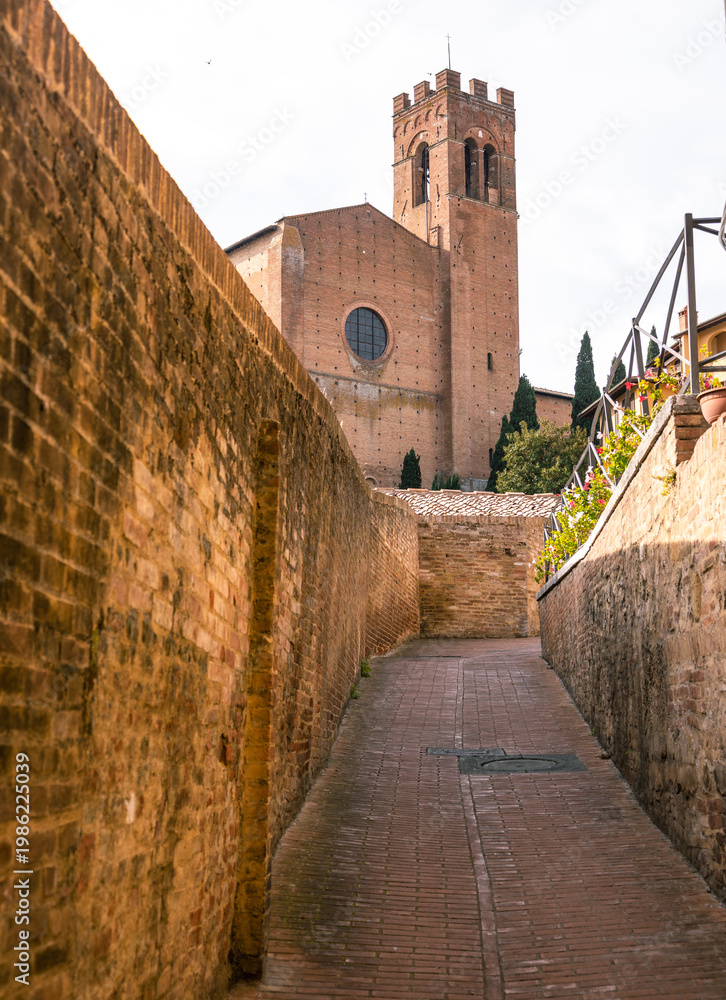 Fototapeta premium Siena alleyway leading to Santo Spirito church bell tower, Italy.