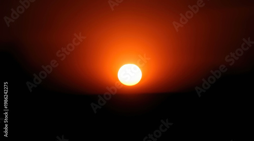 A bright golden sun setting or rising against a dark horizon, warm glowing landscape, dramatic nature scene, peaceful environment.