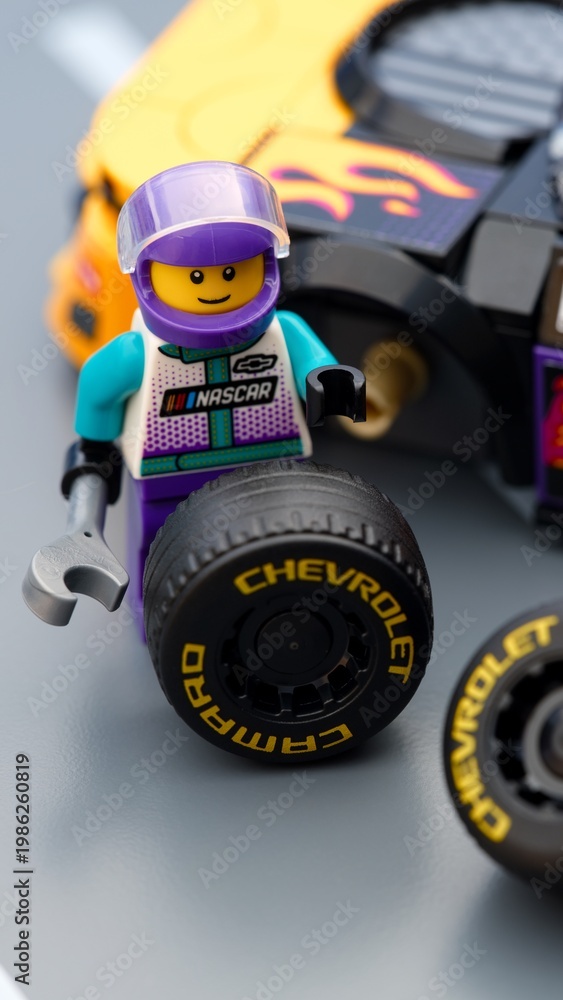 Fototapeta premium Tambov, Russian Federation - January 17, 2026 Lego driver minifigure with wrench changing wheel of a Lego NASCAR Next Gen Chevrolet Camaro ZL car.