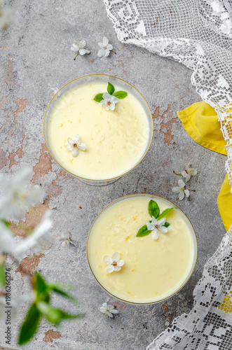 Lemon dessert in a glass, decorated with flowers and leaves. Lemon dessert. Yellow dessert. Lisonne Kurd.