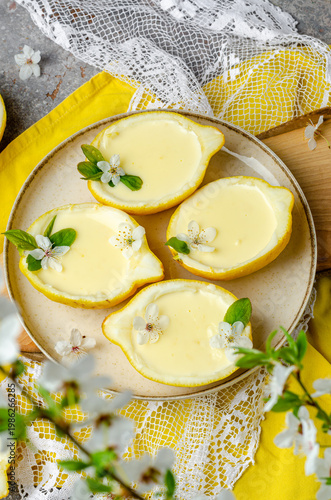 Lemon dessert in a lemon, decorated with flowers and leaves. Lemon dessert. Yellow dessert. Lemon Kurd.