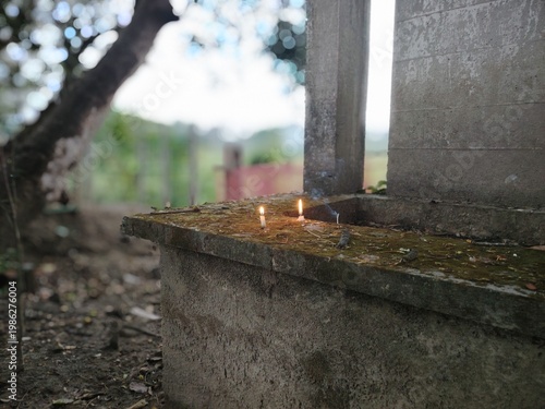 Two small candles are lit on a rough, elevated stone or concrete surface.