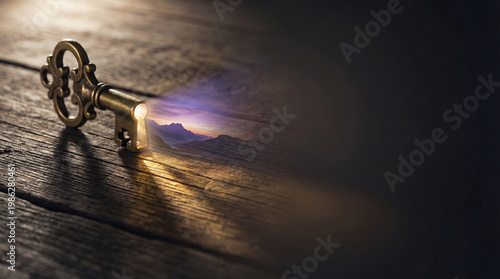 Wide Banner of an Ornate Vintage Key Projecting a Glowing Mountain Landscape at Sunset on a Dark Rustic Wooden Background, Symbolizing Vision and Future