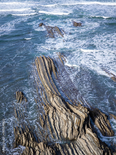 Flysch rock formations meeting ocean waves at coast