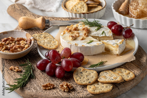 An arrangement of brie with honey served with grapes, nuts and crackers.