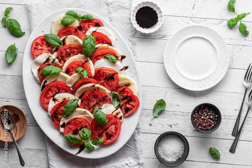A freshly made Caprese salad topped with basil and balsamic glaze.