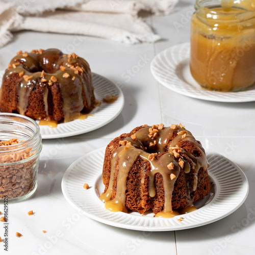 Sticky toffee pudding with caramel drizzled on top, sprinkled with toffee bits.