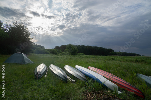 Camping by River with Kayaks Under Dramatic Sky