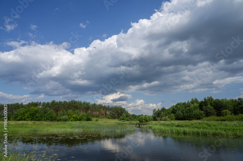 River Landscape with Wooden Bridge under Dramatic Cloudy Sky