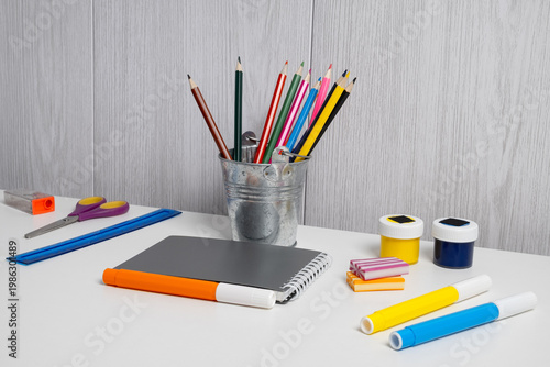Art supplies on a table with colorful pencils, markers, and paper ready for drawing and crafting tasks in a creative space