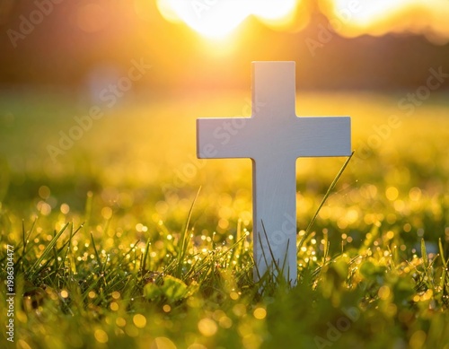 Solemn white cross stands prominently in a vibrant green grassy field, bathed in the warm, golden light of a beautiful sunrise or sunset, symbolizing hope, faith, and remembrance