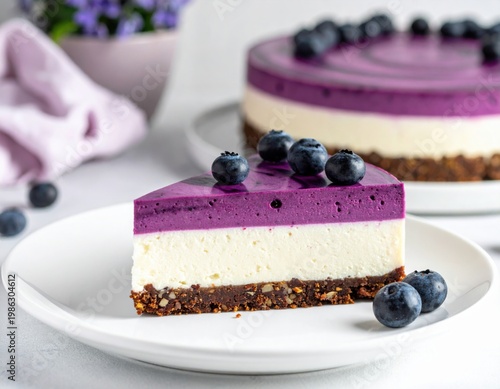 Delicious slice of creamy blueberry cheesecake featuring a vibrant purple top layer and fresh berries on a white plate with the whole cake in the background