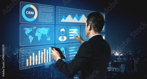 Photos A business executive analyzes data on a digital screen in a modern office setting at night, offering insights into performance and management in a vibrant city backdrop