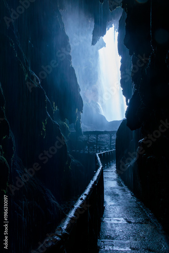 Dark cave leading to powerful waterfall and blue light