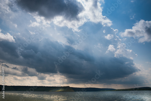 Bay with a high shore. Clouds over the water. Horizon with mountains.
