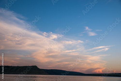 Bay with a high shore. Clouds over the water. Horizon with mountains.