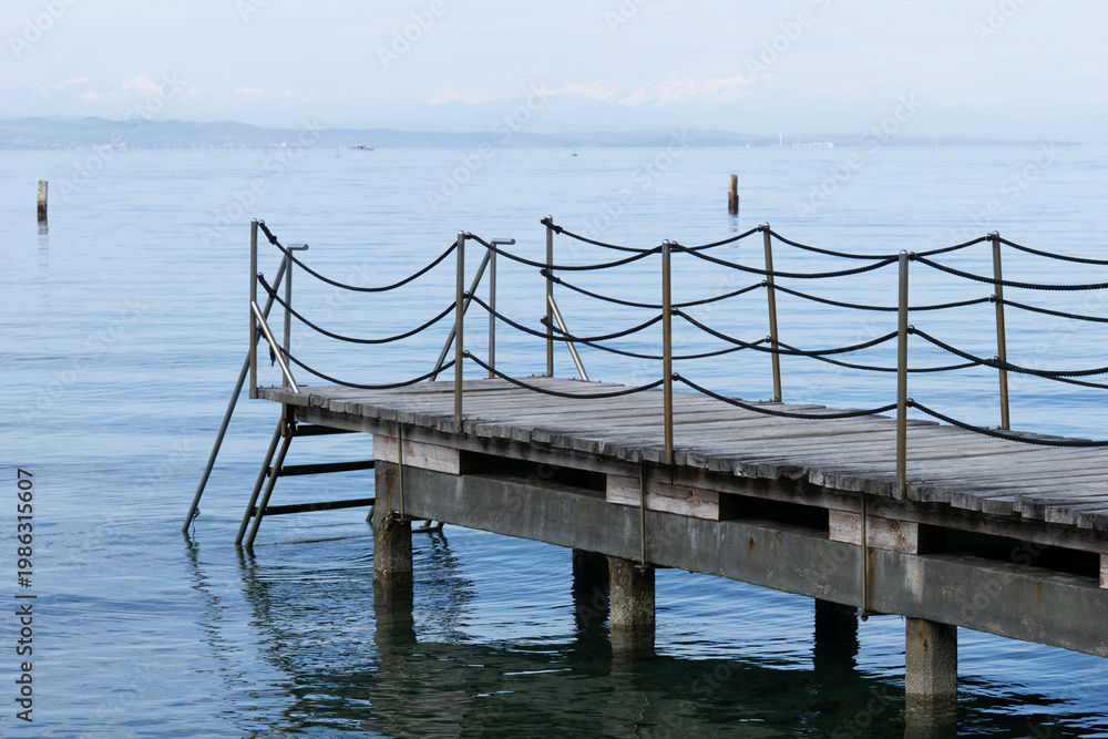 Obraz premium wooden pier bridge blue calm water surface rope railing sea horizon cloudy atmosphere background with copy space for banner design concept of travel, tourism, architecture