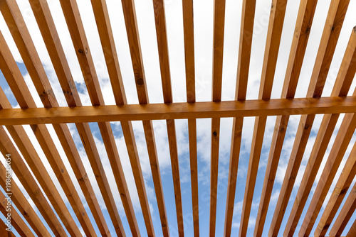 a wooden frame made of logs on the beach in sunny weather against a blue sky with clouds, part of a wooden frame building under construction on the beach to create a good infrastructure