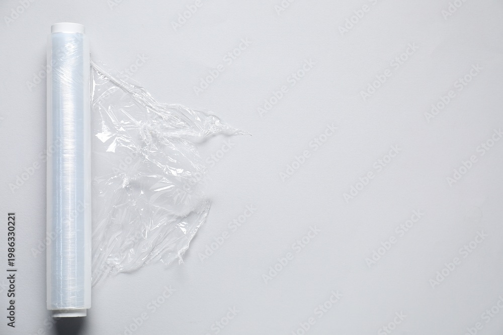 Naklejka premium Roll of cling film on light background, top view. Space for text