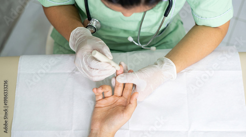 Top down view of a nurse testing patient's blood sugar using a lancing device.