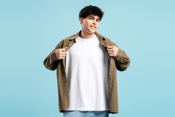 Young man posing showing white t shirt on blue background
