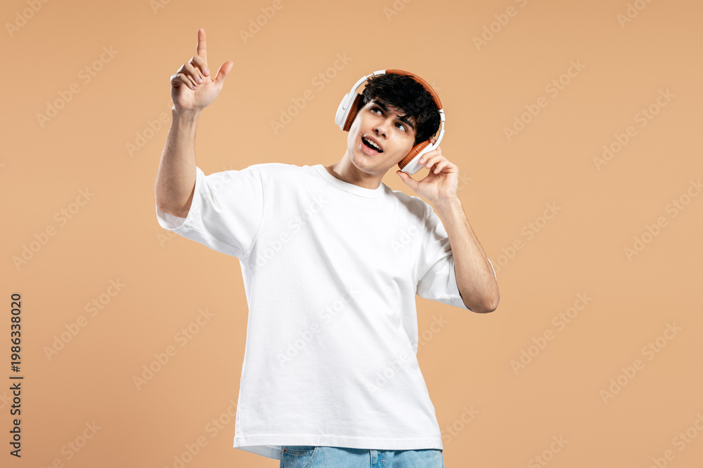Fototapeta premium Young man listening music pointing finger up expressing joy
