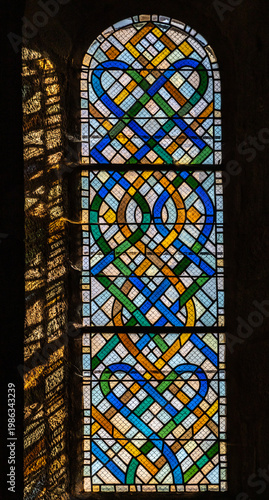 Cornil (Corrèze, Nouvelle aquitaine, France) - Détail de vitrail avec entrelacs colorés de l'église Saint-Etienne
