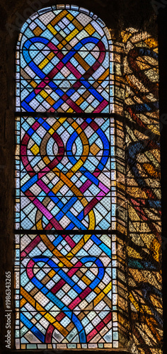 Cornil (Corrèze, Nouvelle aquitaine, France) - Détail de vitrail avec entrelacs colorés de l'église Saint-Etienne